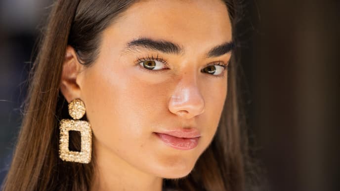 Frau mit Sommerteint und braunen offenen Haaren sowie großen Ohrringen.