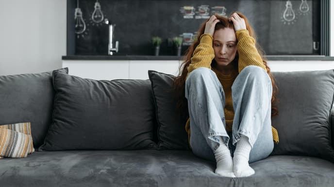 Frau sitzt gestresst auf dem Sofa