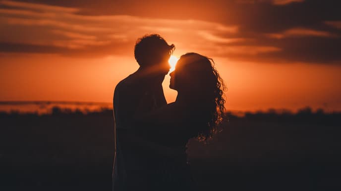 Mann und Frau umarmen sich mit Sonnenuntergang im Hintergrund