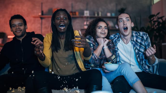Gruppe von Freunden guckt Fernsehen und erschreckt sich