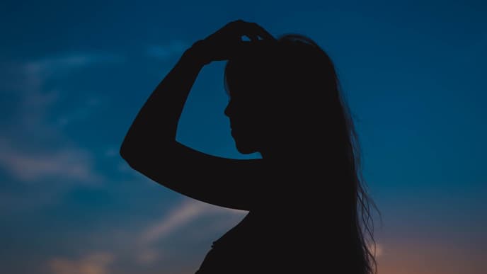 Silhouette einer Frau mit langen Haaren in der Dämmerung