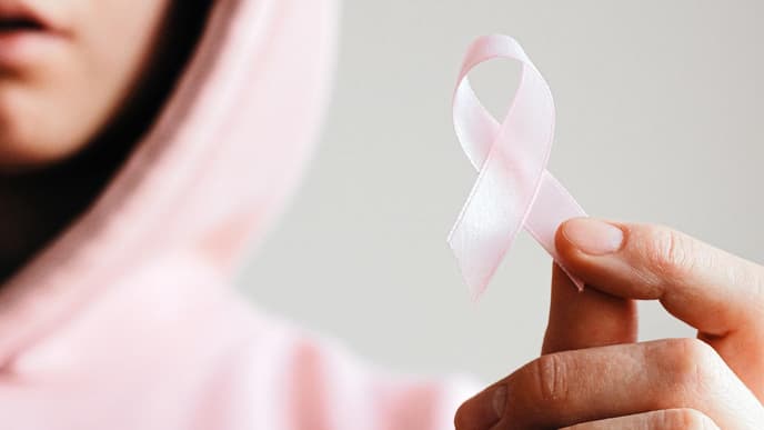 Frau mit pinkem Hoodie hält eine pinke Schleife in der Hand