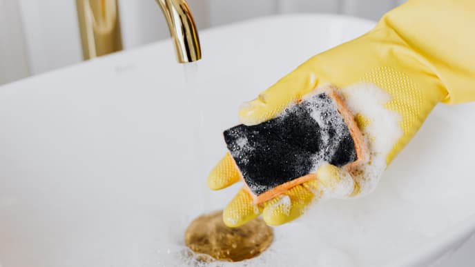 Gelber Handschuh mit Schwamm im Waschbecken