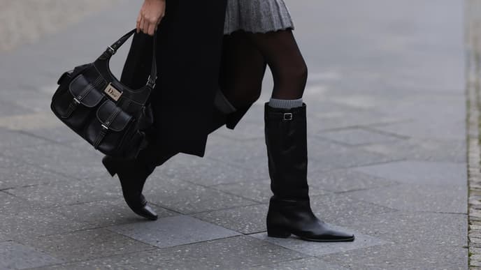 Frau trägt Stiefel und Dior-Tasche
