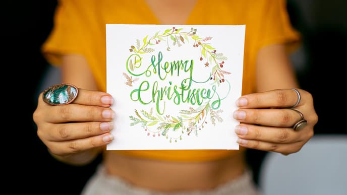 Frau hält eine Weihnachtskarte mit Weihnachtswünschen in der Hand
