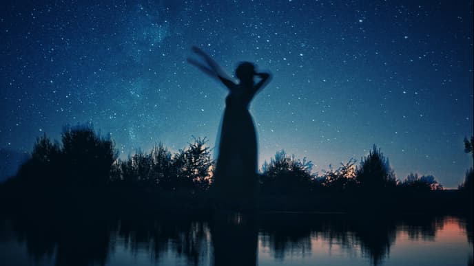 Schattenbild einer Frau an einem See in der Nacht