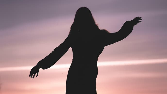 Silhouette einer Frau im Kleid während eines Sonnenuntergangs