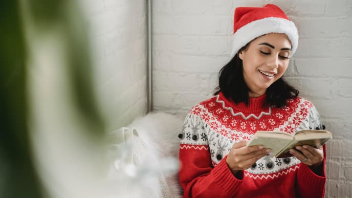 Frau im Weihnachtspullover liest ein Buch