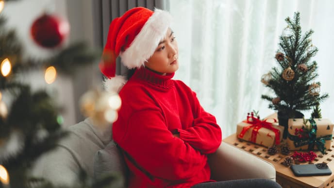 Frau mit Weihnachtsmütze sitzt auf dem Sofa