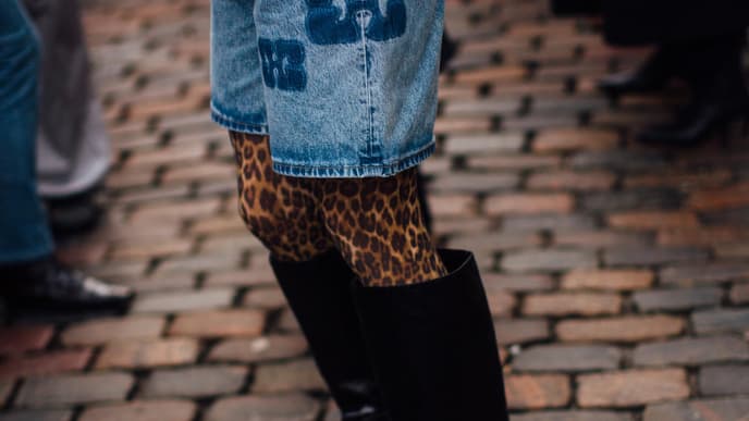 Frau trägt auf Copenhagen Fashion Week Jeans Kombi und Leomuster Strumpfhose und spitze schwarze Stiefel