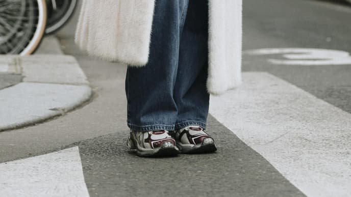 Frau trägt auf Paris Fashion Week weißen Fake Fur Mantel Jeans und Sneaker
