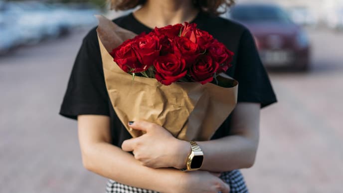 Frau hält einen Strauß mit roten Rosen in der Hand