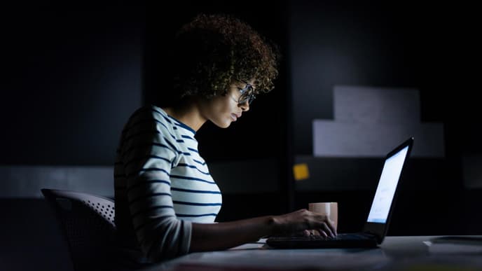 Junge Frau sitzt nachts am Laptop