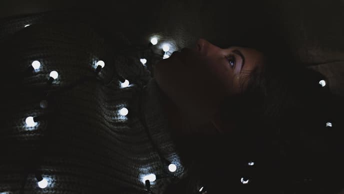 Frau liegt mit einer Lichterkette auf dem Boden
