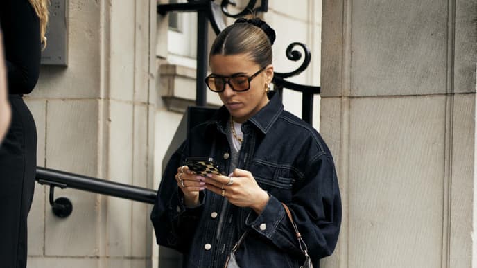 Frau mit Retro-Sonnenbrille schaut auf ihr Handy