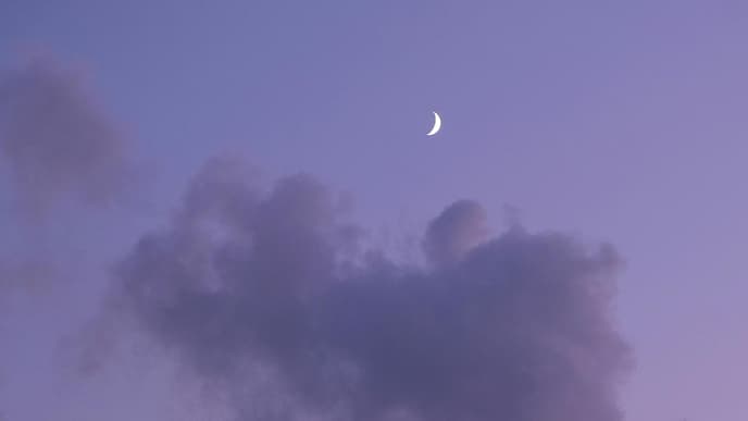 Halbmond am lilafarbenen Himmel mit Wolken