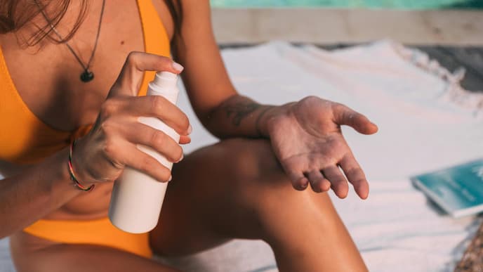 Frau im gelben Bikini trägt Sonnenschutz auf