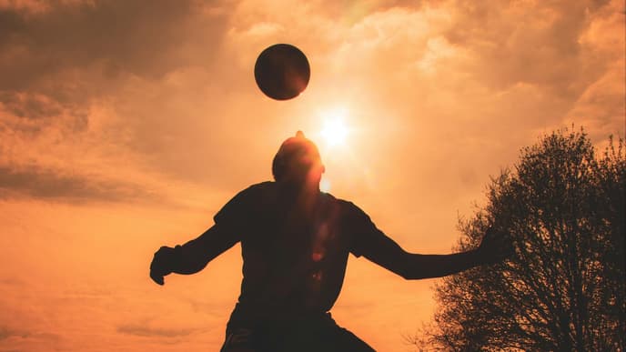 Person spielt Fußball im Sonnenuntergang