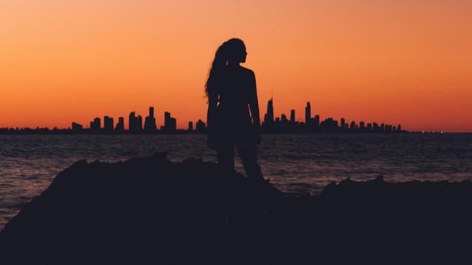 Frau steht vor einer Skyline während des Sonnenuntergangs