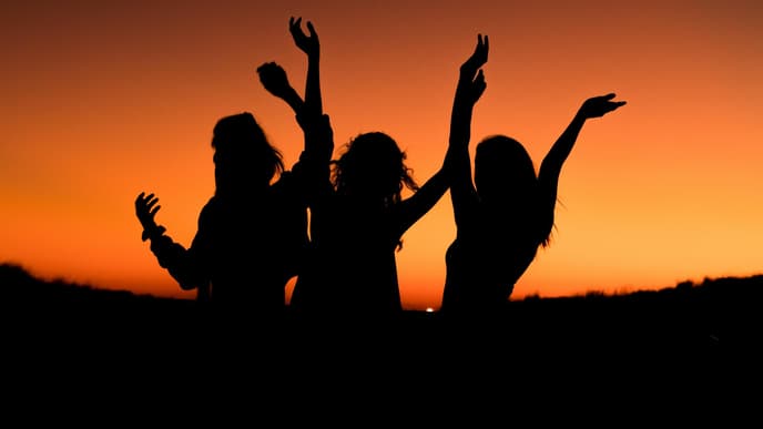 Drei Silhouetten von Frauen vor Sonnenuntergang