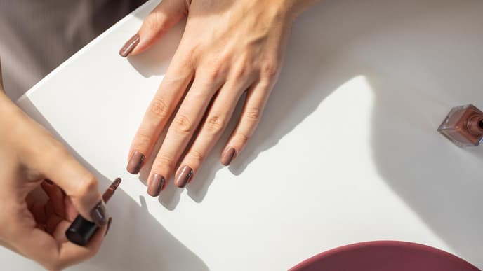 Ahornsirup-Naegel: Frau traegt braunen Nagellack auf