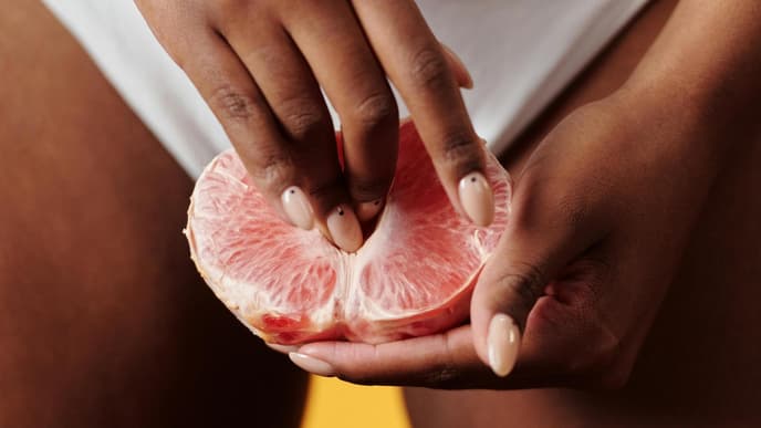 Person hält Finger an Grapefruit