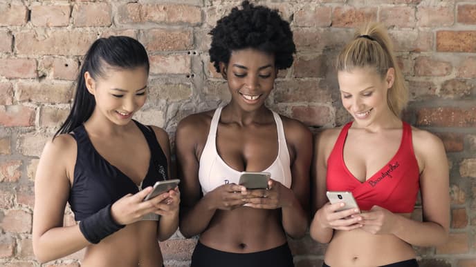 Drei junge Frauen schreiben auf ihren Smartphones