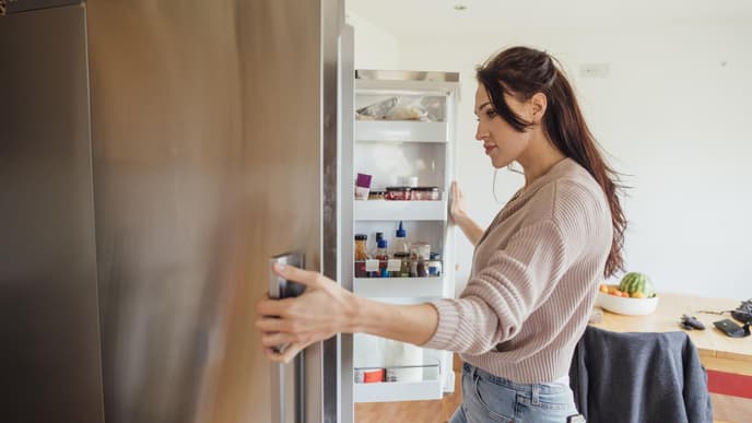 Eine Frau steht vor einem offenen Kühlrschrank