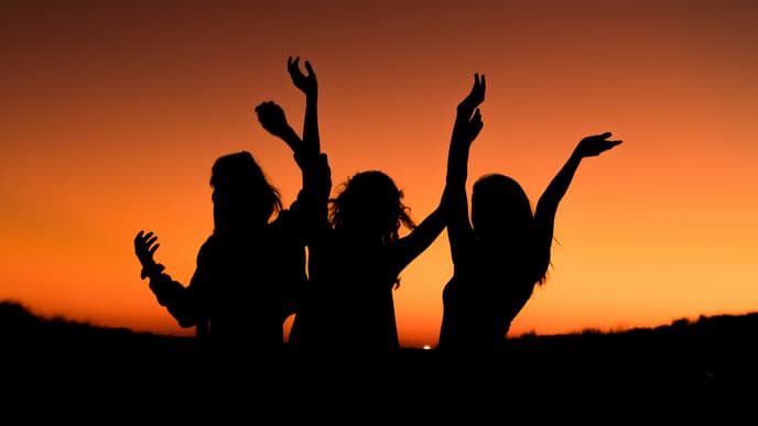 Drei Frauen tanzen unter dem Abendhimmel