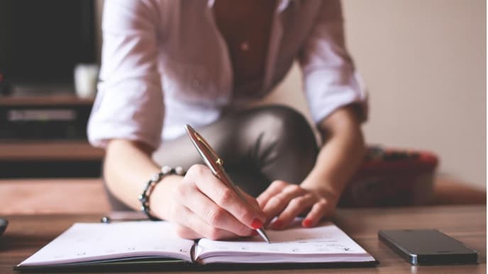 Eine Frau schreibt in ihr Notizbuch