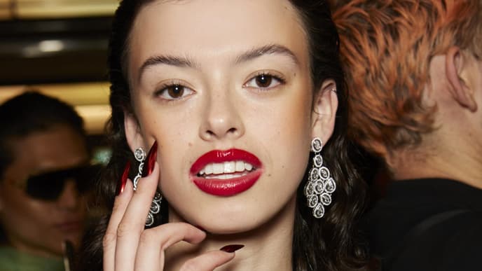 Frau mit roten Lippen, großen Ohrringen und roten Nägeln.