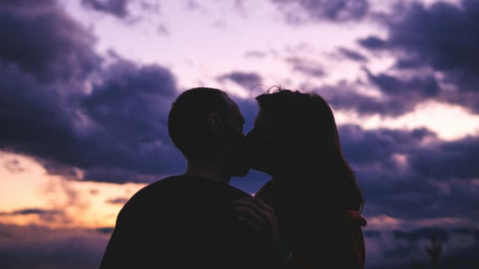 Paar küsst sich vor lila Abendhimmel