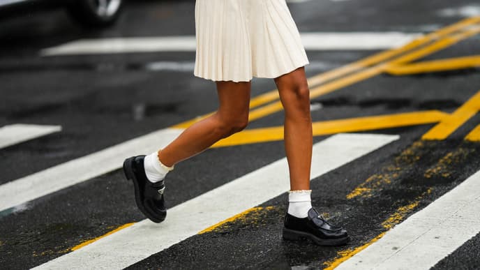 Frau traegt Rock mit Loafern und weißen Socken