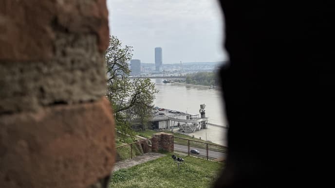 Ein Blick durch einen Mauerspalt auf einen Fluss und die Waterfront in Belgrad.