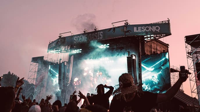 Festival-Bühne bei rosafarbener Dämmerung mit Feuerwerk am Himmel.