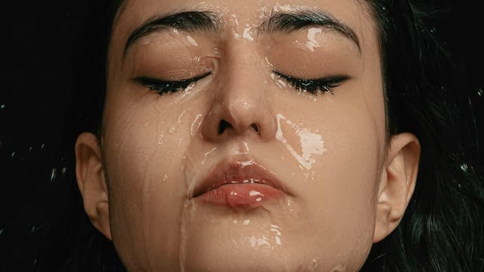 Einer Frau mit geschlossenen Augen läuft Wasser über das komplette Gesicht.