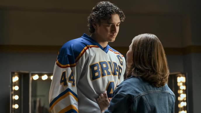 Garrett Graham und Hannah Wells sind das Serien-Traumpaar in „Off Campus“. Ein junger Mann im Eishockey-Trikot steht einer jungen Frau in Jeansjacke gegenüber und guckt zu ihr herunter.