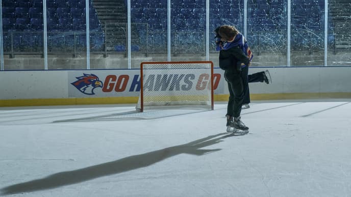 Ein Mann und eine Frau fallen sich auf einem Eishockeyfeld in die Arme.