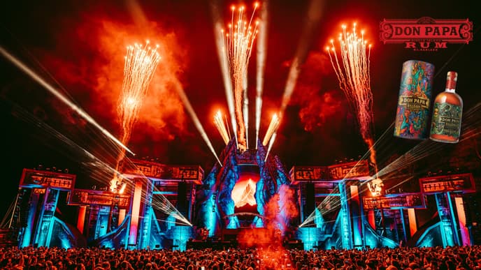 Eine Festivalbühne mit Feuerwerk und einer Menschenmenge davor.