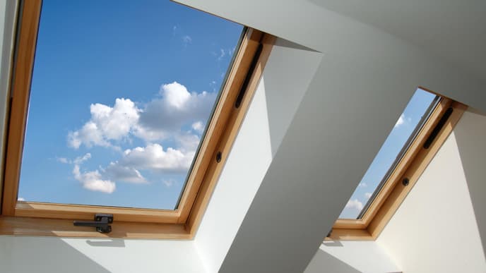 Dachgeschoss Fenster aus Holz mit Blick auf den blauen Himmel mit Wolken.