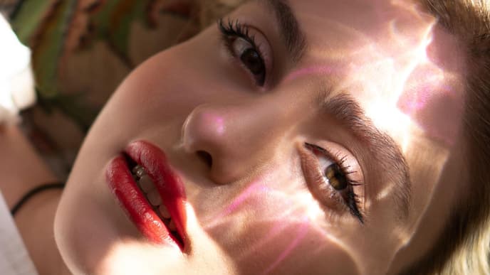 Frau mit glänzendem Lippenstift und Sonne im Gesicht