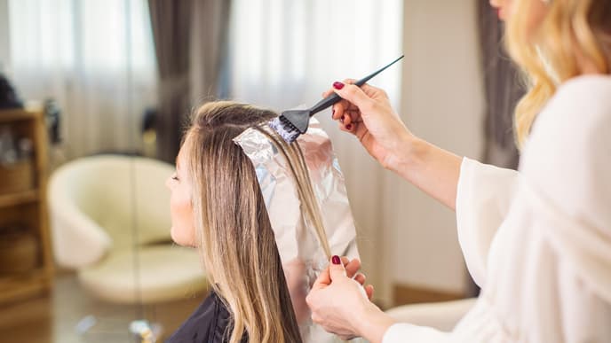 Eine Frau färbt ihre Haare beim Friseur