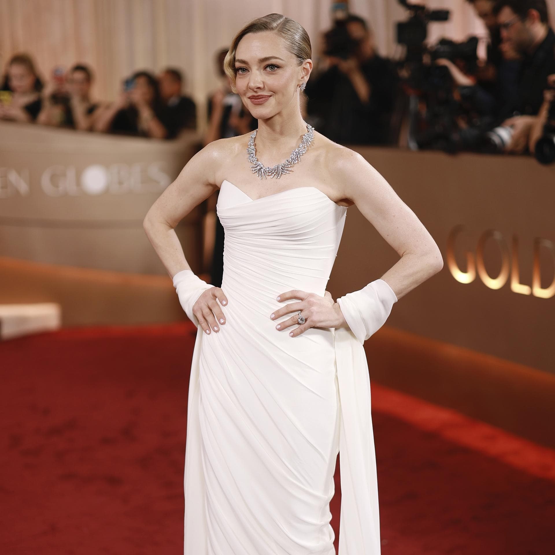 Amanda Seyfried mit eleganter Hochsteckfrisur und einer hellen Robe.