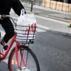 Rotes Fahrrad mit H&M-Tüte im Fahrradkorb auf Straße