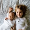 Ein Baby und ein Kleinkind liegen auf einem Bett