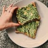 Hand, die nach zwei Avocado Toasts greift