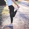 Frau dehnt sich im Wald mit einer Fitbit am Handgelenk