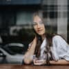 Frau sitzt hinter Fensterscheibe