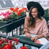 Frau sitzt auf Balkon mit Laptop
