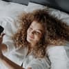 Frau im Bett mit einem Handy